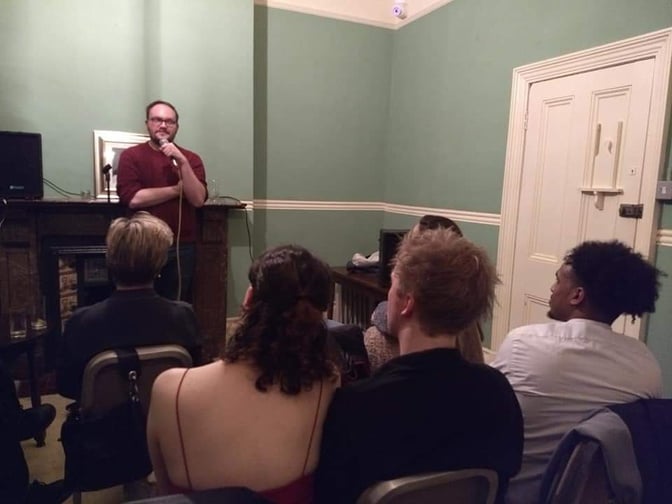 Coach Chris Jones giving a speech to a group of people in a room.